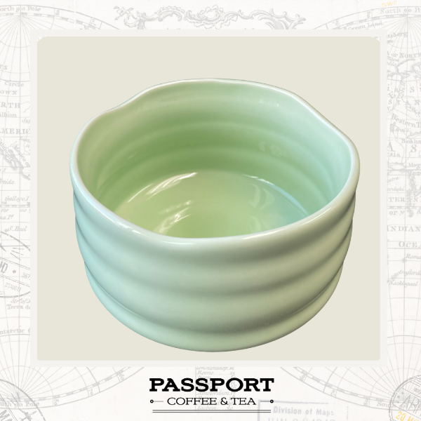 A light green ceramic tea bowl with a scalloped rim and horizontal ridges