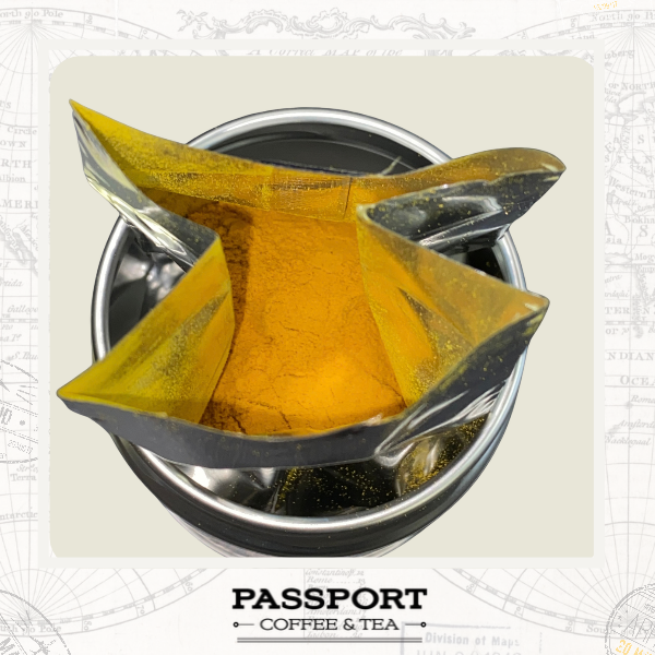 A top-down view of a metallic travel tumbler with a clear paper cone filter filled with bright yellow-orange powder, set against a light beige graphic background with a faint map design and the text 'PASSPORT COFFEE & TEA' at the bottom.
